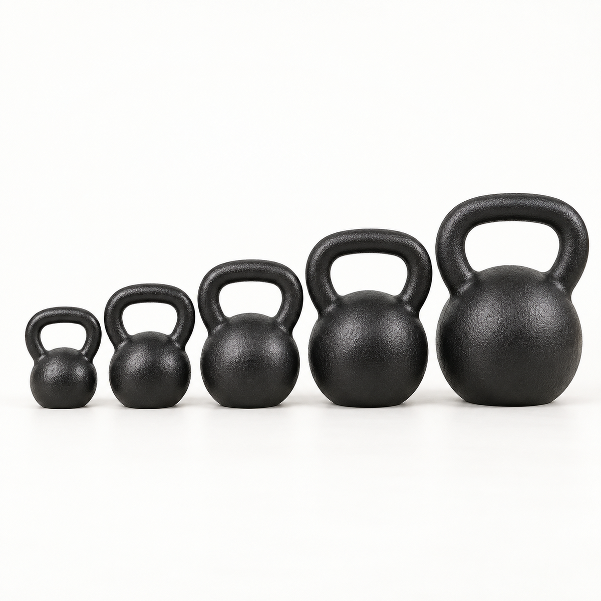 Graduated lineup of matte-black cast-iron kettlebells on a light studio background.